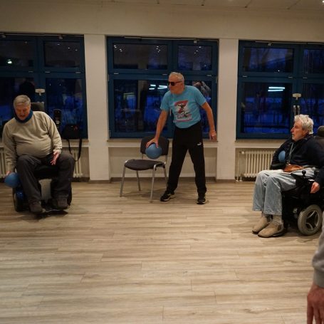 Frau im Rollstuhl beim Training mit kleinen Hanteln.